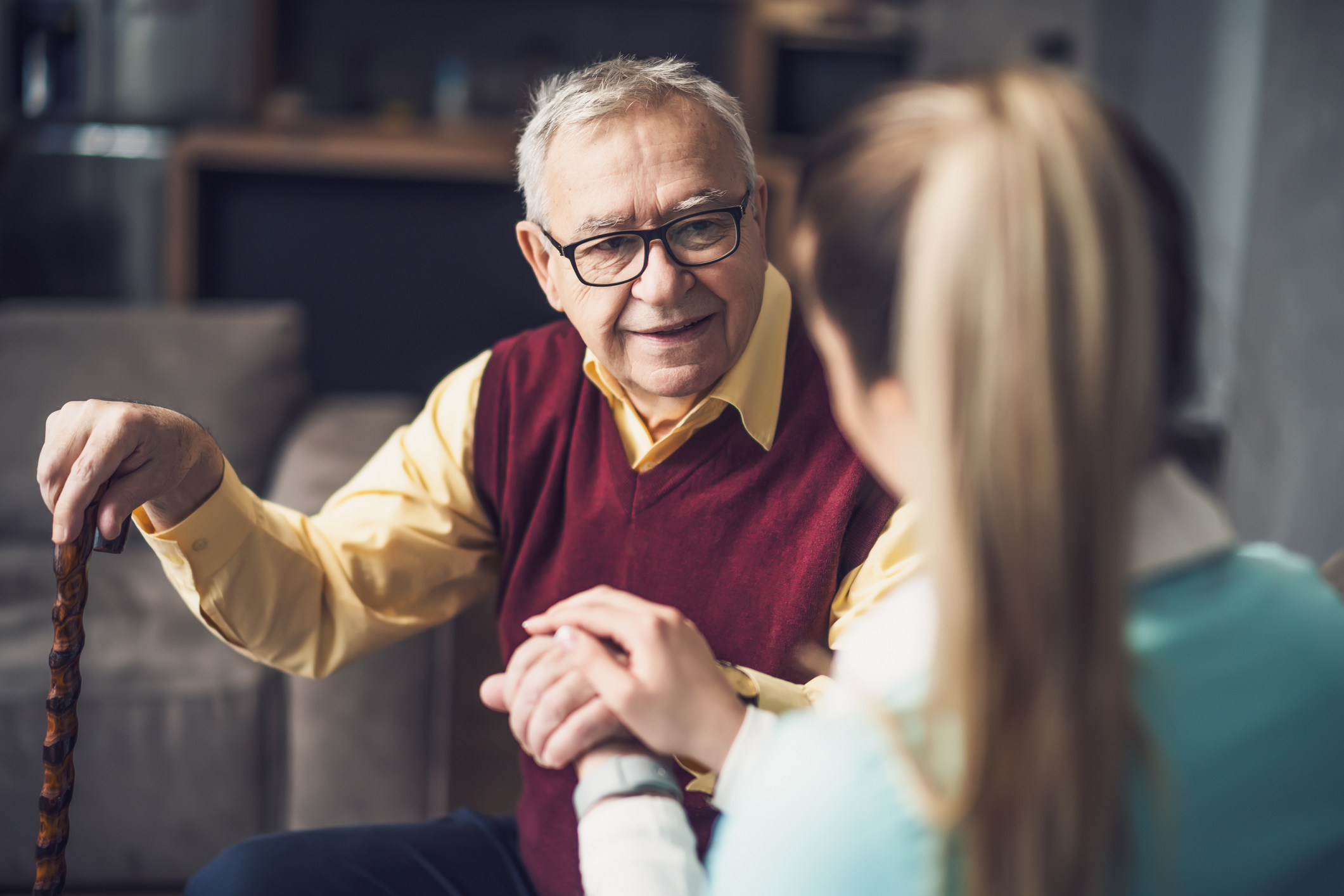 Senior with care manager, sitting in his living room and talking.